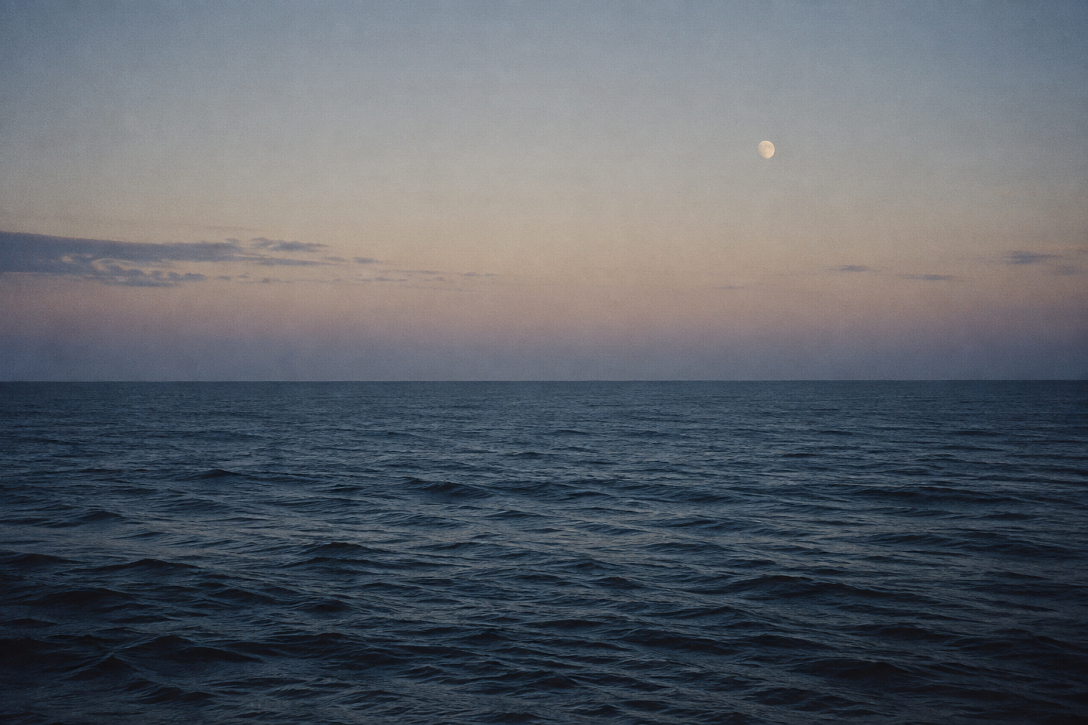 A quiet ocean beneath a pale evening sky